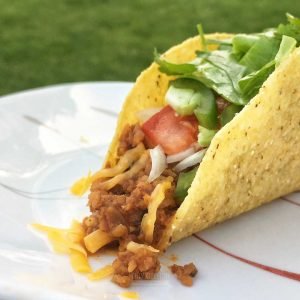 A hardshell TexMex vegetarian taco with lettuce, tomato, and cheese on a plate.