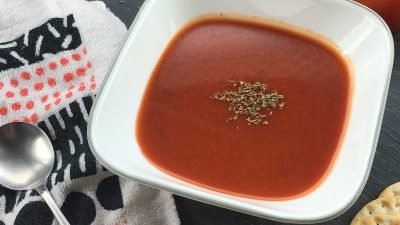 A bowl of tomato soup with a sprinkle of basil.