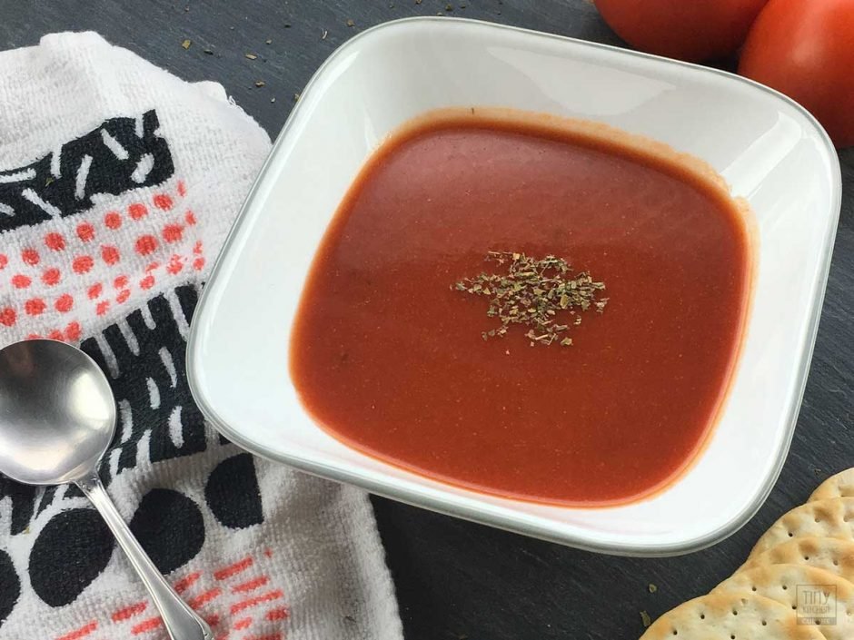 A bowl of tomato soup with a sprinkle of basil.