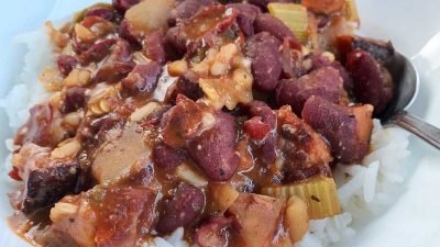 A bowl of stewed red kidney beans and sausage over rice.
