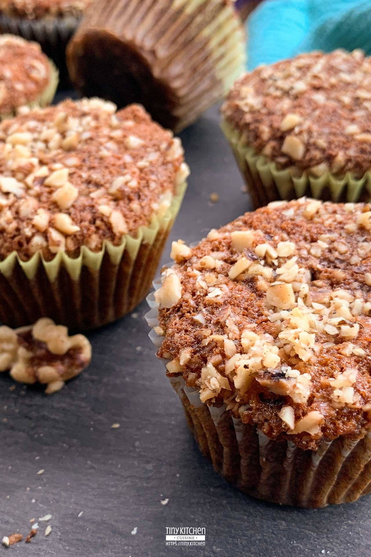 Banana nut muffins topped with walnuts laid out on a slate board.